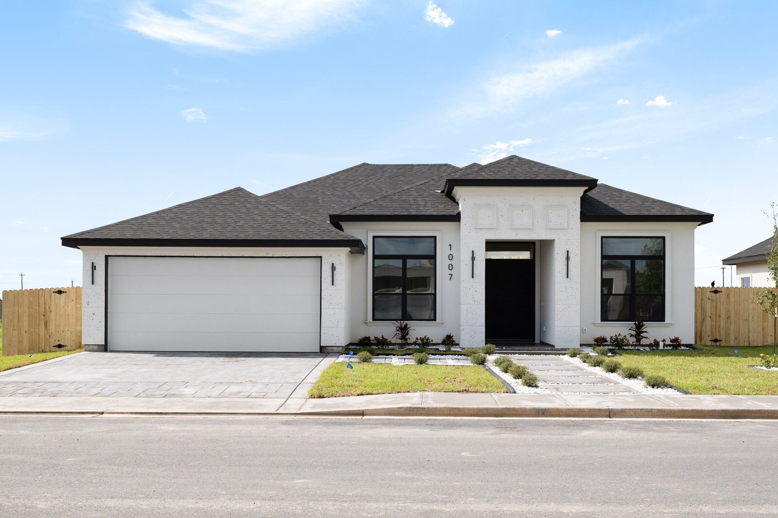 Newly completed single-story custom home with a two-car garage on a clear day.