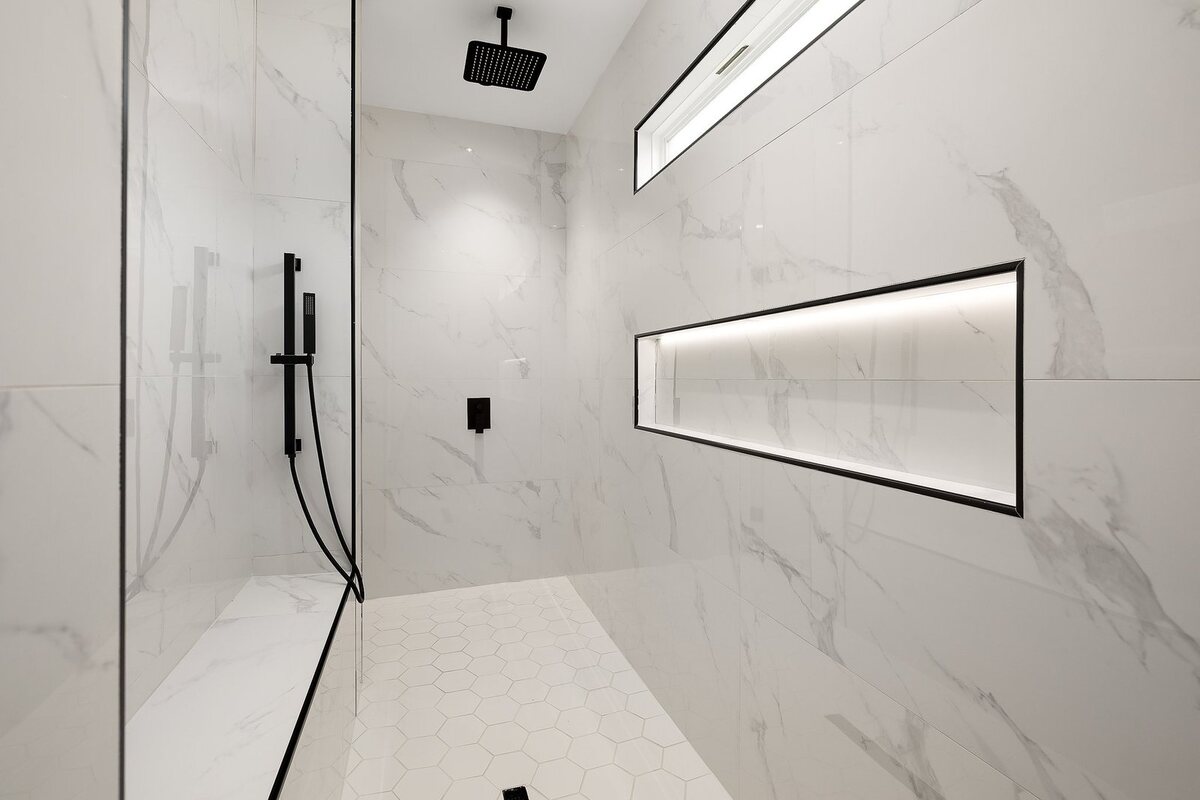Walk-in shower with marble tile and black fixtures